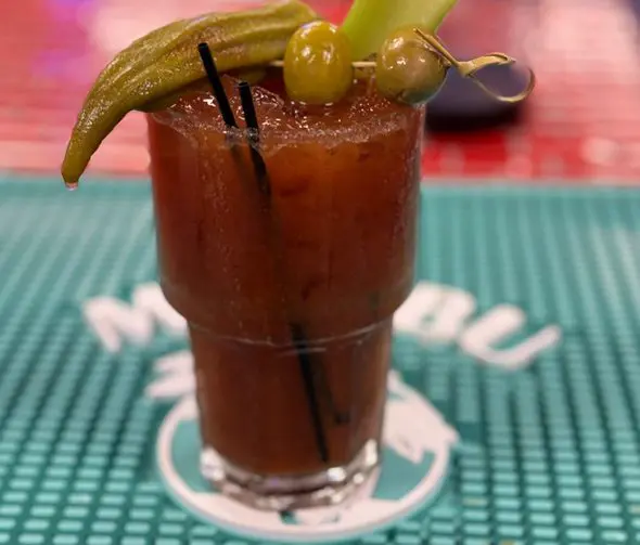 A bloody mary with pickles and a pickle on top.