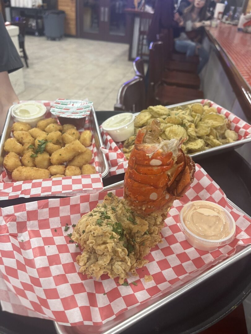 A table with three trays of food and two drinks.